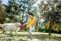 Donna matura che gioca con il cane su un prato — Foto stock