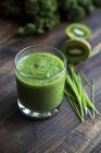 Kale smoothie with kiwi and organic raygras on wood — Stock Photo