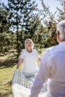 Elderly couple holding picnic blanket on a meadow — Stock Photo