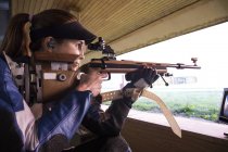 Женщина со спортивной винтовкой в тире — стоковое фото