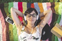 Rilassata giovane donna sdraiata su una coperta ad ascoltare musica — Foto stock