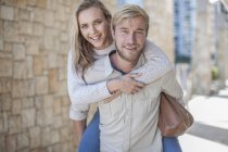Happy young couple, woman riding piggyback — Stock Photo