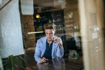 Young man sitting in a bar ooking at his cell phone — Stock Photo