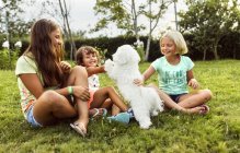 Tre bambine che giocano con un cucciolo all'aperto — Foto stock