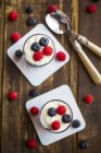Joghurt mit rotem Fruchtgelee, Blaubeeren und Himbeeren in Gläsern auf Holz — Stockfoto