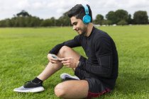 Handsome caucasian sporty man listening music in headphones outdoors — Stock Photo