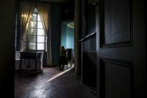 Молодая женщина сидит в мрачной комнате — стоковое фото