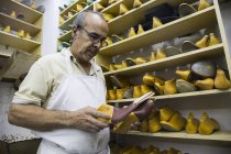 Shoemaker selecting shoe lasts from a shelf in his workshop — Stock Photo