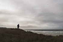 Человек, стоящий на берегу под облачным небом — стоковое фото