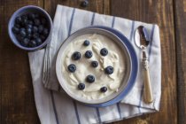 Yogurt with blueberries in bowl on wood — Stock Photo