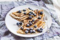 Crepes with blueberries sprinkled with icing sugar on plate — Stock Photo