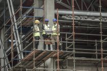 Bauarbeiter und Geschäftsmann diskutieren Bauplan auf Baugerüst — Stockfoto