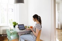 Beautiful caucasian brunette woman working on laptop at home — Stock Photo
