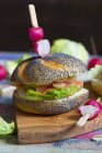 Poppy seed roll with cream cheese, lettuce leaf, salmon and onion rings garnished — Stock Photo