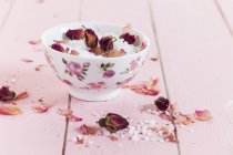 Крупный план морской соли с сушеными цветами роз в чаше — стоковое фото