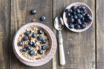 Ciotola di muesli ai mirtilli con bacche di lupo su legno scuro — Foto stock