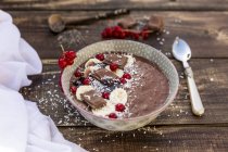 Bowl of banana and chocolate smoothie with red currants and grated coconut — Stock Photo