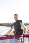 Uomo sorridente sulla spiaggia che tiene la tavola da surf — Foto stock