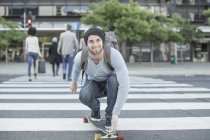 Young man skateboarding on zebra crossing — Stock Photo