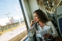 Smiling woman on a train using a tablet — Stock Photo