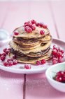 Stack of American pancakes with red currants sprinkled with icing sugar — Stock Photo