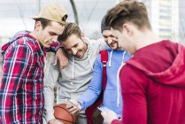Giovani giocatori di basket che condividono smartphone — Foto stock
