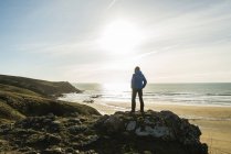 Man standing on rock at the coast at sunset — Stock Photo