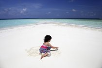 Мальдивы, девушка играет на пляже на мелководье — стоковое фото
