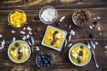 Bowls of mango smoothie with diced mango, coconut flakes, blueberries and choco crunch — Stock Photo