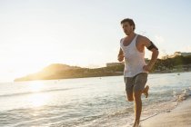 Jovem homem correndo na praia de manhã — Fotografia de Stock