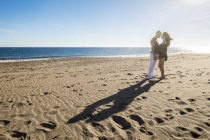 Feliz pareja de pie cara a cara en la playa a la luz de fondo - foto de stock