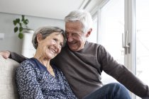 Happy senior couple sitting together on the couch at living room — Stock Photo