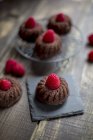 Mini cakes with raspberries on cooling grid and slate — Stock Photo