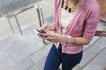 Imagen recortada de la joven chica casual caminando con teléfono inteligente en las manos - foto de stock