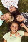 Quattro bambine sdraiate sull'erba — Foto stock