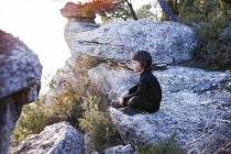 Bambino seduto su una roccia e guardando la vista — Foto stock