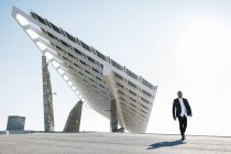 Empresario caminando en la ciudad con panel solar sobre fondo - foto de stock