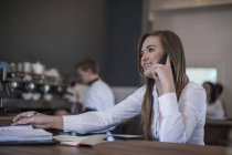 Young woman sitting at coffee bar working — Stock Photo