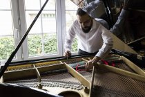 Adult bearded piano tuner tuning grand piano — Stock Photo