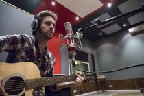 Man playing guitar in a recording studio during a musical recording — Stock Photo