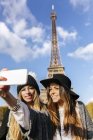 France, Paris, deux femmes souriantes prenant un selfie avec la Tour Eiffel en arrière-plan — Photo de stock