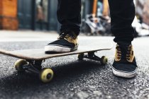 Обрезанный образ молодого человека со скейтбордом на городской улице — стоковое фото