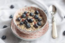 Bowl of blueberry muesli with wolf-berries on white fabric — Stock Photo