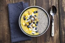 Bowl of mango smoothie with diced mango, coconut flakes, blueberries, choco crunch and chia — Stock Photo