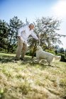 Uomo anziano che gioca con cane su un prato — Foto stock