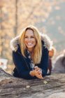 Donna felice godersi l'autunno nella foresta appoggiata sul tronco d'albero — Foto stock