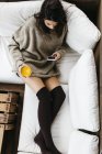 Donna rilassante con smartphone e bicchiere di succo d'arancia — Foto stock