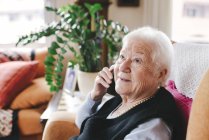 Portrait de femme âgée souriante téléphonant avec smartphone à la maison — Photo de stock