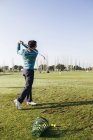 Golfista bater uma bola de golfe na área de condução de um clube de golfe — Fotografia de Stock