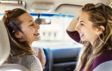 Juguetonas mujeres jóvenes sobresaliendo lengua en el coche - foto de stock